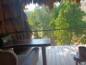 埃尔莱马特Alice Guesthouse的阳台配有桌子,享有树林美景
