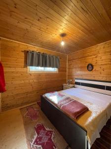 佩尔梅特Origjina Farm的木制客房内的一间卧室配有一张大床
