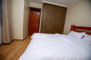 MeruWHITE LOTUS EXECUTIVE APARTMENT的卧室配有一张白色大床和木门