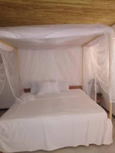 Palmarinla villa sur la plage的一间卧室配有一张带天蓬的白色床