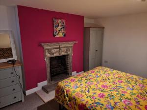 伦敦Entire Ground Floor Flat, Free Off-Street Parking and Large Garden的一间卧室设有粉红色的墙壁和壁炉