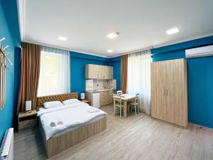 安布罗劳里Khidikari Hotel的一间卧室设有蓝色的墙壁、一张床和一张书桌