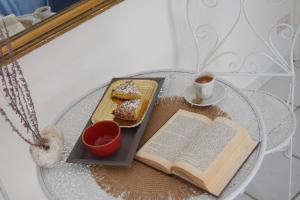 马蒂纳塔Casetta nel centro storico的桌子,桌子上放着书,盘子上放着食物,喝着咖啡
