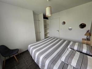 多勒Maison de la forêt的卧室配有条纹床和椅子