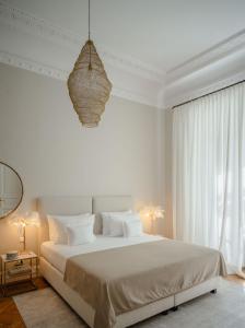 维也纳Roosevelt Stadthaus的白色卧室配有一张大床和吊灯