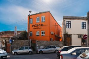 波尔图Peach Hostel & Suites的一座橙色的建筑,汽车停在停车场