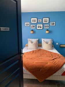 ThenayGîte La Cabuche proche du zoo de Beauval的蓝色卧室,配有带橙色棉被的床