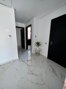 马拉喀什Appartement Prestigia 3 chambres的一间铺有大理石地板并配有黑色门的客厅