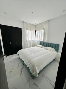 马拉喀什Appartement Prestigia 3 chambres的白色卧室设有一张大床,铺有大理石地板。