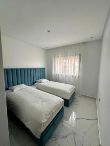 马拉喀什Appartement Prestigia 3 chambres的客房内设有两张床,铺有大理石地板。