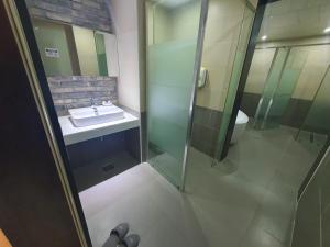 釜山Yeonsan Oops Hotel的一间带水槽和玻璃淋浴的浴室
