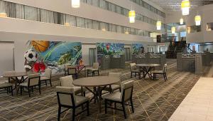 弗林特Gateway Hotel & Convention Center Grand Blanc Flint Airport Michigan的一间设有桌椅和足球壁画的自助餐厅