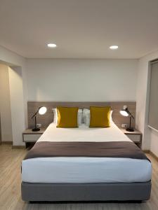 波哥大Palermo Home Bogota & Art Gallery的一间卧室配有一张大床和两张黄色枕头