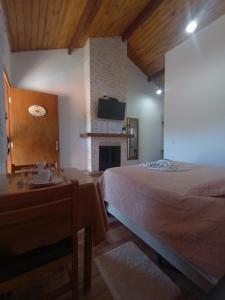 蒙特韦尔迪Recanto lavinia的一间卧室配有一张床、一张桌子和一个壁炉