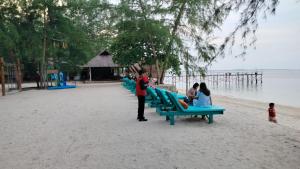 丹戎槟榔Madu Tiga Beach and Resort的一群人坐在海滩上的长椅上