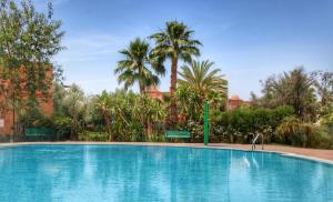 马拉喀什La Perle de l'Atlas by Golf Resort的一座棕榈树环绕的大型游泳池
