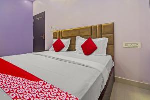 斋浦尔Hotel Krishna Palace的一间卧室配有一张带红色枕头的大床
