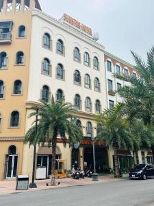 下龙湾Sunstar Hotel的一座白色的大建筑,前面有棕榈树