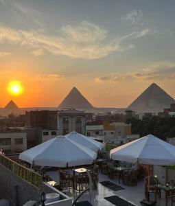 开罗King of Pharaohs INN pyramids的日落时分带桌子和遮阳伞的屋顶露台