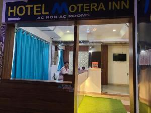 艾哈迈达巴德Hotel Motera Inn的坐在酒店柜台上的男人