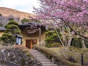 伊豆Hanare Yado Yosizumi的一座房子,设有楼梯,通往带粉红色花朵的门