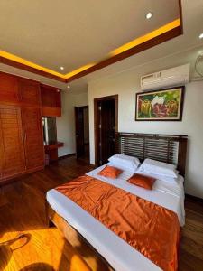 曼巴豪Camiguin Lanzones Resort的一间卧室配有一张带橙色毯子的大床