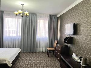 比什凯克Sultan的酒店客房配有一张床、一把椅子和一台电视。