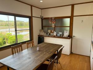 壹岐市ikibase Guest House的一间带木桌和窗户的用餐室