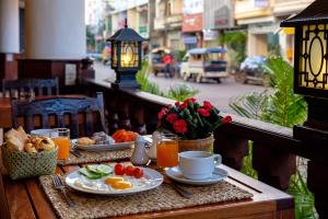 巴色Pakse hotel & Restaurant的阳台上的桌子上摆着早餐食品和饮料