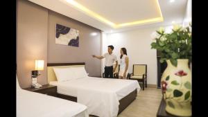 岑山Khách Sạn Sen Biển Sầm Sơn的一名男子和女子站在带两张床的酒店房间