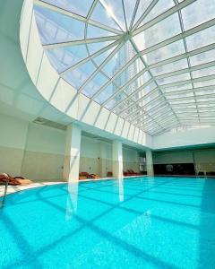 斯科普里Skopje Sky City 19th Floor Twin Apartments with Indoor Pool & Spa & Fitness Including in Price的一个带玻璃天花板的大型游泳池