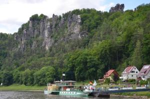 柯尼希施泰因易北Ferieneinrichtungen-Haus-am-Stein的一条河上的小船,山底下