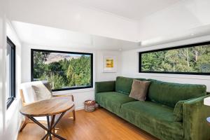 Hawea FlatTiny Home on 1 Acre Land in Picturesque Hawea Flat的客厅设有绿色沙发和2个大窗户
