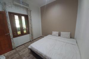 普禾加多OYO 93892 Homestay Koe Syariah的卧室配有白色的床和窗户。
