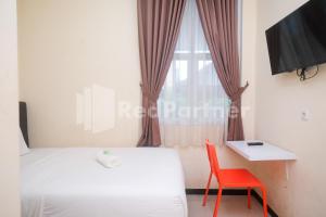 三宝垄Griya Loka 2 Syariah Near Simpang Lima Mitra Reddoorz的一间卧室配有一张床、一张红色椅子和一个窗户
