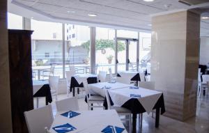 埃斯卡纳Paraiso Beach by Hoteles Centric -Adult Only的餐厅配有白色的桌椅和蓝色的餐巾