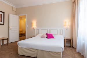 勒芒The Originals City, Hôtel Chantecler, Le Mans的卧室配有一张带两个粉红色枕头的大型白色床。