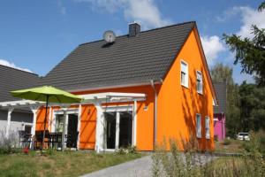 勒伯尔K 105 - Ferienhaus für die ganze Familie mit Kamin in Röbel an der Müritz的一座橙色房子,前面有一把伞
