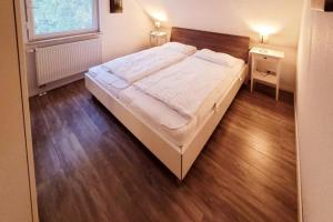 马林费尔德K 96 OG - charmante Ferienwohnung mit Badewanne und Sauna in Roebel Mueritz的卧室内的一张大床,铺有木地板