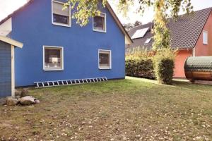 马林费尔德K 96 OG - charmante Ferienwohnung mit Badewanne und Sauna in Roebel Mueritz的蓝色的房子,前面有院子