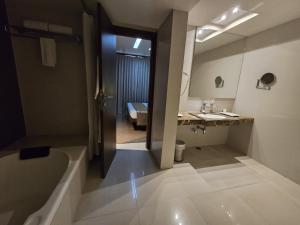 古瓦哈提Hotel Daaysco Oley Allo的带浴缸、水槽和镜子的浴室