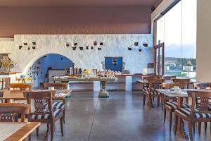 圣巴尔托洛梅卡塞里奥德莫扎佳乡间别墅酒店的餐厅设有木桌、椅子和大窗户。
