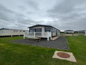 LongniddryLovely 2-Bed Caravan in Prestonpans的一个小房子,设有门廊和长凳