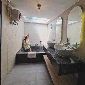 Phumĭ Prêk ChreyPrivate Villa的坐在带两个盥洗盆的浴室的柜台上的女人