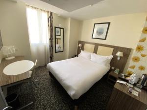 巴黎Holiday Inn Paris Opéra - Grands Boulevards, an IHG Hotel的酒店客房设有一张大床和一张桌子。