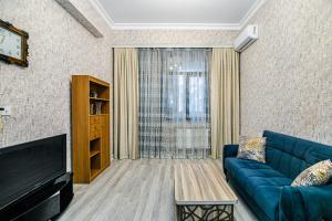 巴库Deluxe Apartment 128/34的客厅配有蓝色的沙发和电视