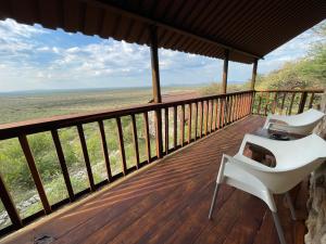 奥奇瓦龙戈Aloegrove Safari Lodge的木甲板上配有白色椅子的门廊
