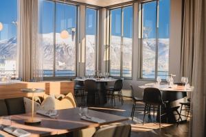 特罗姆瑟Enter St Elisabeth Suites & Spa的餐厅配有桌椅,位于山脉的背景中。