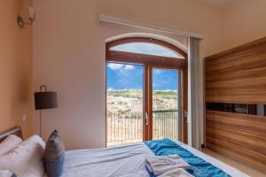 MġarrHarbour Views Gozitan Villa Shared Pool - Happy Rentals的一间卧室设有一张床和一个大窗户
