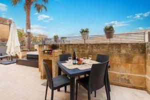 MġarrHarbour Views Gozitan Villa Shared Pool - Happy Rentals的庭院里配有桌椅和一瓶葡萄酒